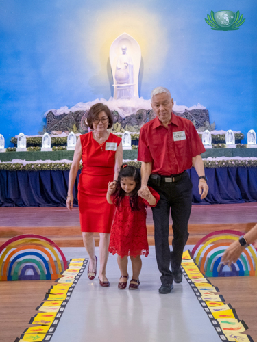 Student Aleksia Alezandra Ong holds her grandparents’ hands while they walk down the runway.