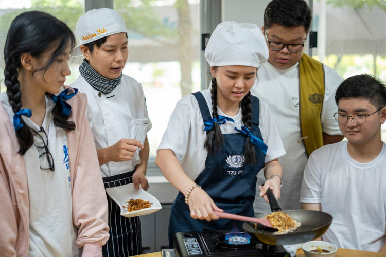 At the 2024 Tzu Chi Youth Camp, Martina Yeh (second from left) goes from table to table to teach campers how to prepare a simple meatless dish.