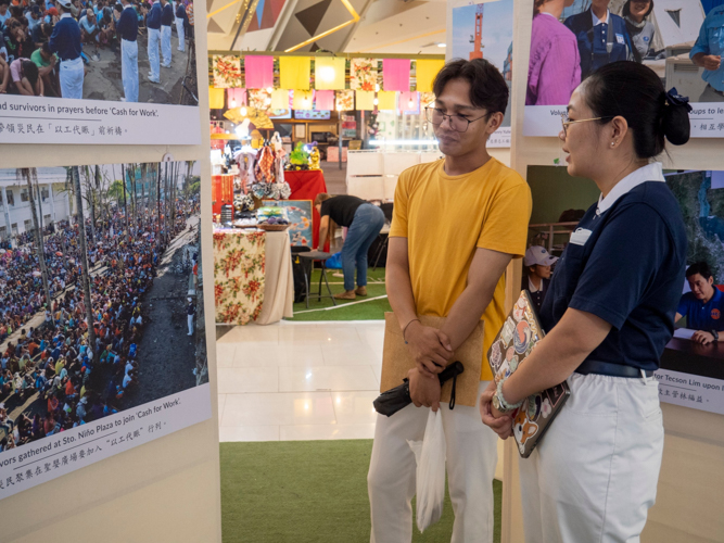 Shoppers stop to look at the pictures, recalling perhaps their own painful memories of the Category 5 storm.  【Photo by Matt Serrano】