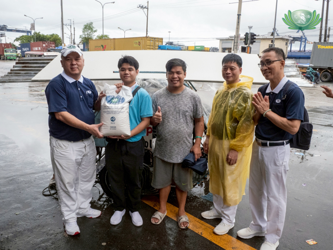 Tzu Chi volunteers presented scholar Karl Andrew Bonabon (second from left) with basic provisions and construction materials.