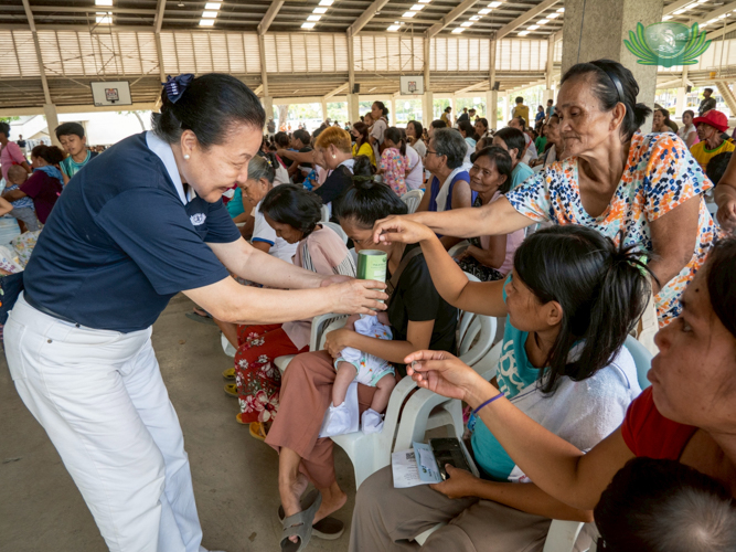 Senior citizens eagerly place their donations in a Tzu Chi coin can.