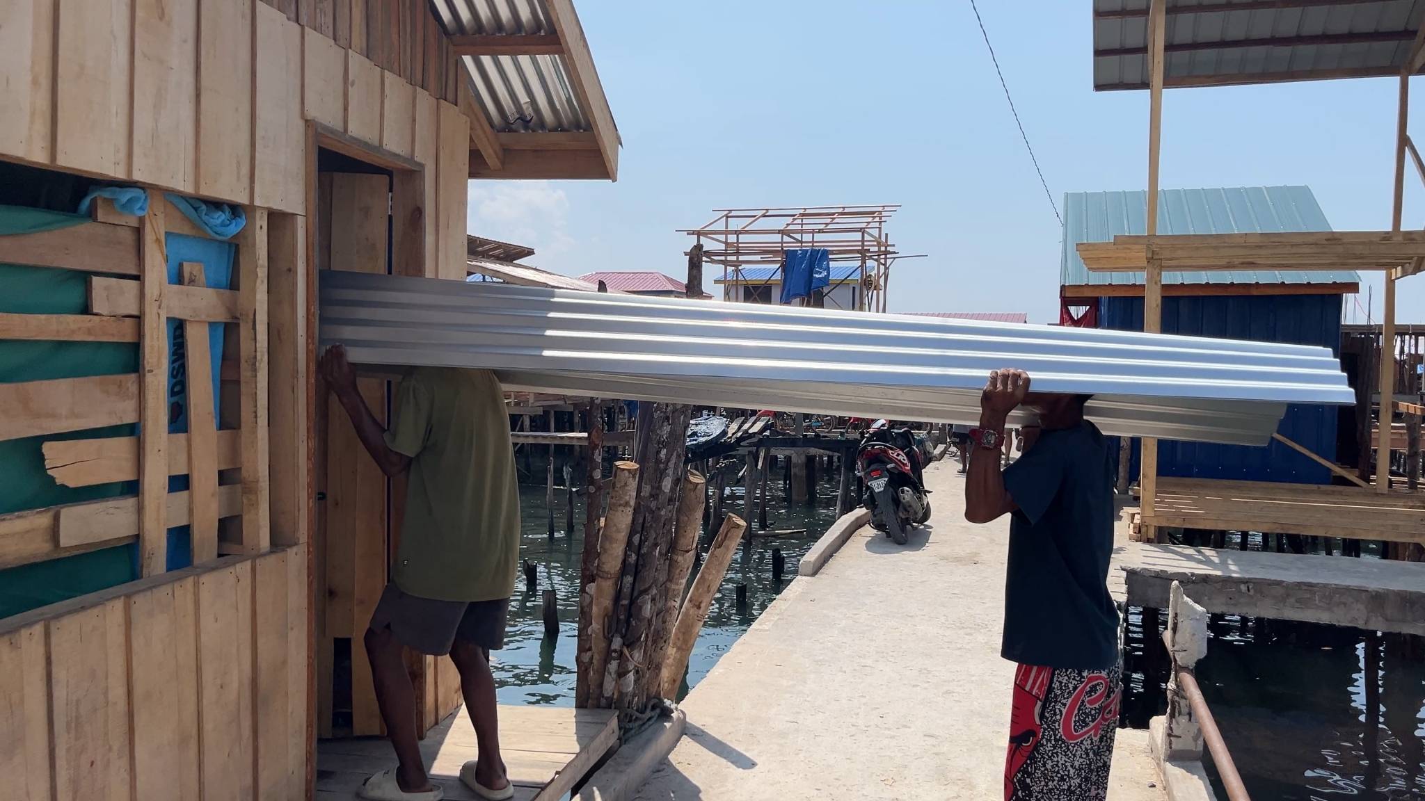 Beneficiaries carefully secure their roofing materials for future repair of their house.