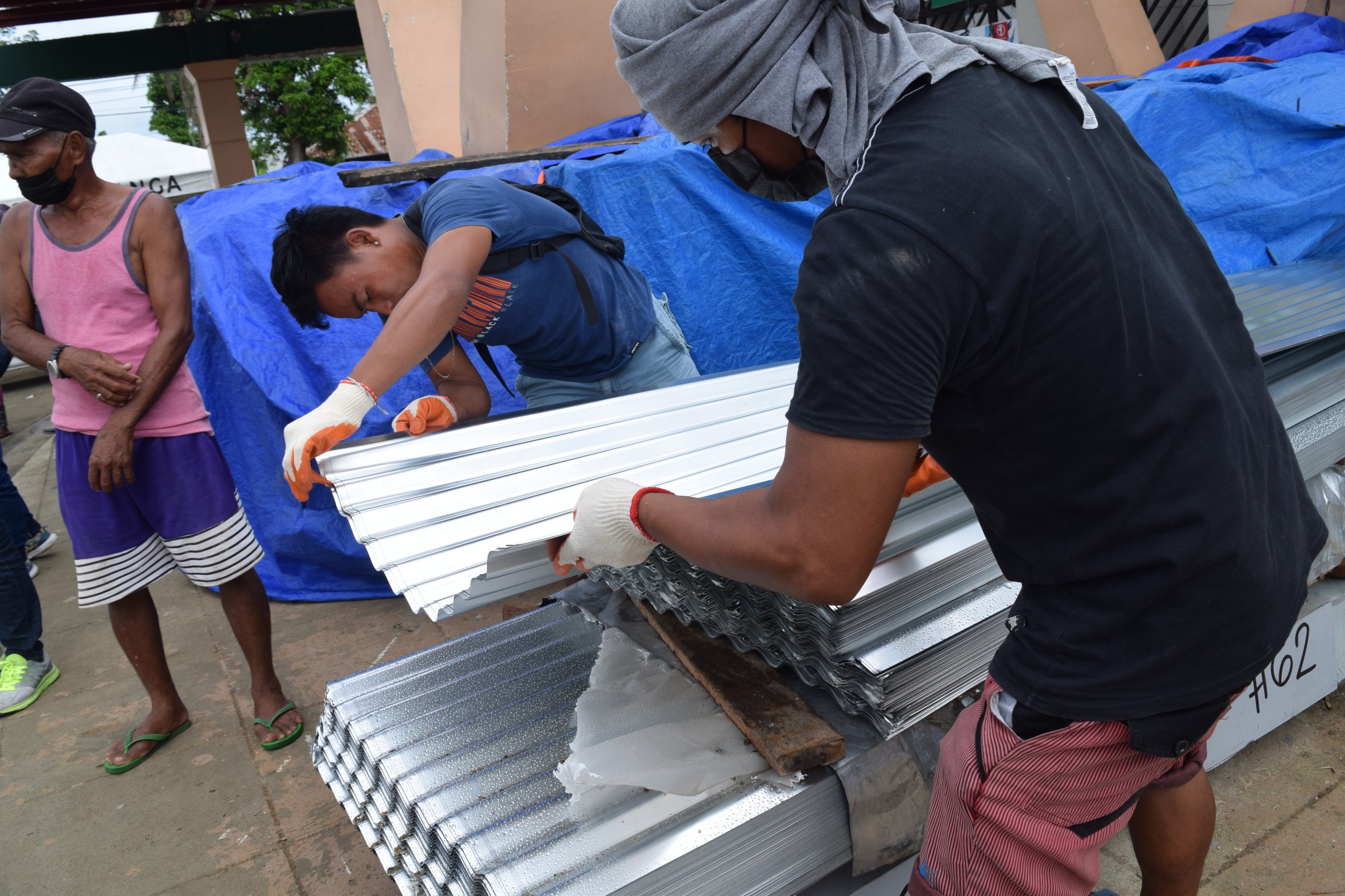 Volunteers pile up GI sheets donated by Tzu Chi Foundation for distribution. 