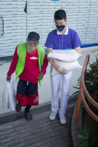 A Tzu Chi Youth volunteer assists a tricycle driver with his sack of rice. 【Photo by Matt Serrano】