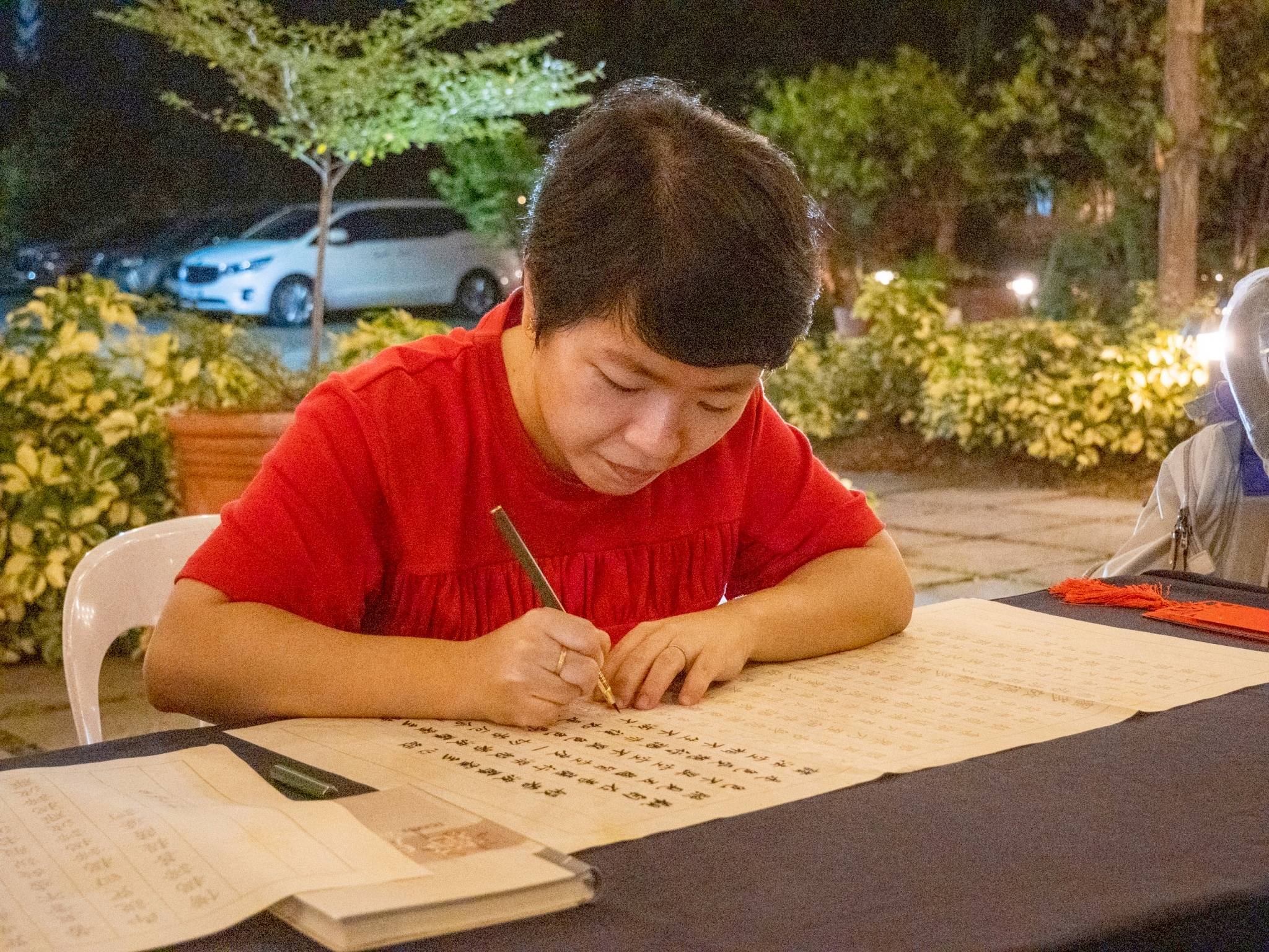 Eva Cu, attending for the first time, expresses joy in completing her calligraphy.