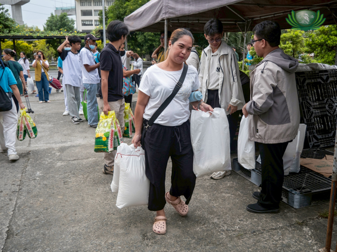 A medical beneficiary carries 20 kg of rice along with other grocery items, ready to take them home after the event.