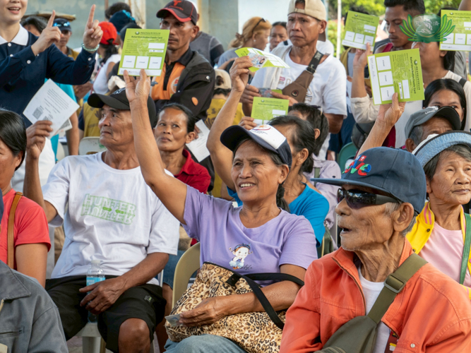 Beneficiary Inocencia Gelaver (in purple) is happy to receive relief from Tzu Chi and grateful for the early blessings for the holidays.