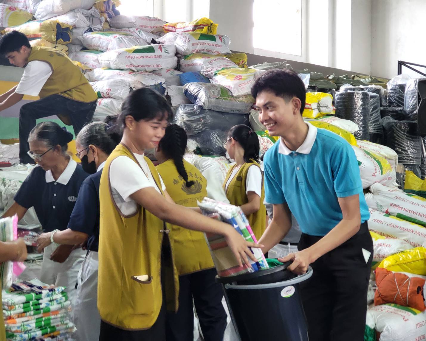 Before attending Humanity class, Tzu Chi scholar Axcel Rivera (right) received relief goods from a Tzu Chi volunteer as one of the survivors of the monsoon floods caused by Typhoon Carina (Gaemi) in the San Mateo, Rizal, area.