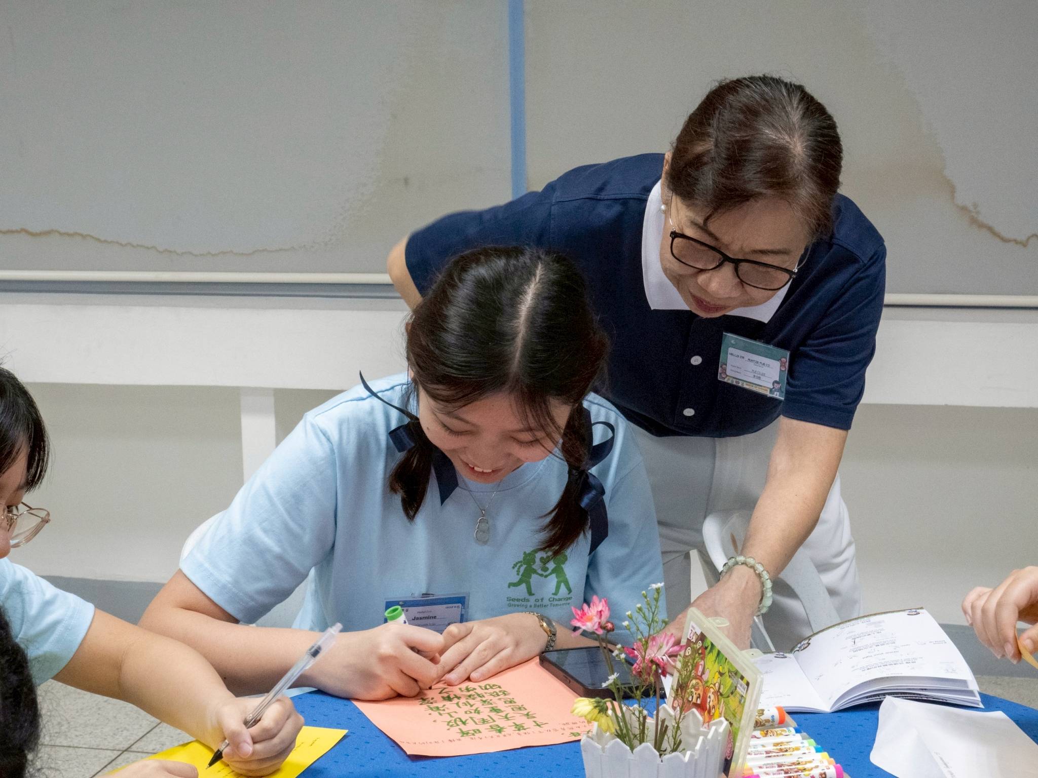 Tzu Chi volunteer Pue Chin Lee Chua looks over a camper writing a letter to her parents after an emotional presentation of filial piety.
