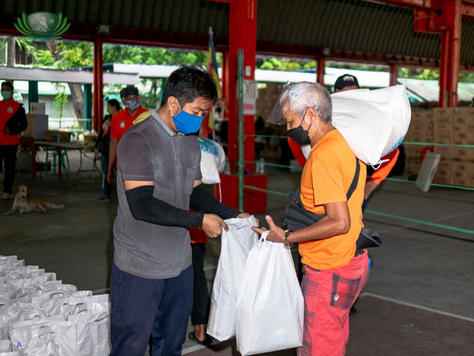 A Tzu Chi volunteer hands bags of grocery items to a driver beneficiary. 【Photo by Daniel Lazar】