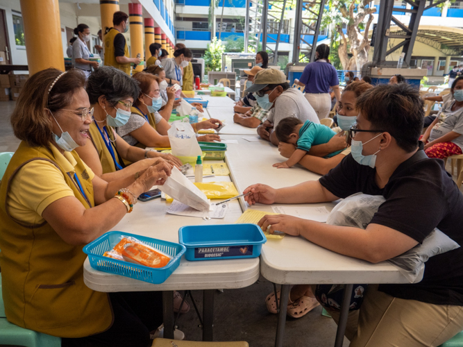 Sporting Tzu Chi vests, local volunteers happily assist medical mission beneficiaries.【Photo by Matt Serrano】