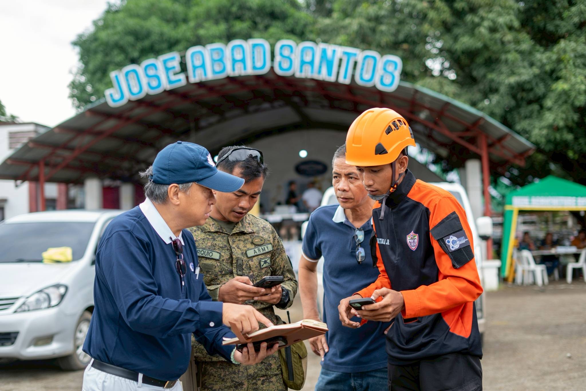Tzu Chi volunteer Johnny Kwok coordinates with representatives from the Philippine Army and National Disaster Risk Reduction and Management Council during an ocular visit in Jose Abad Santos. 