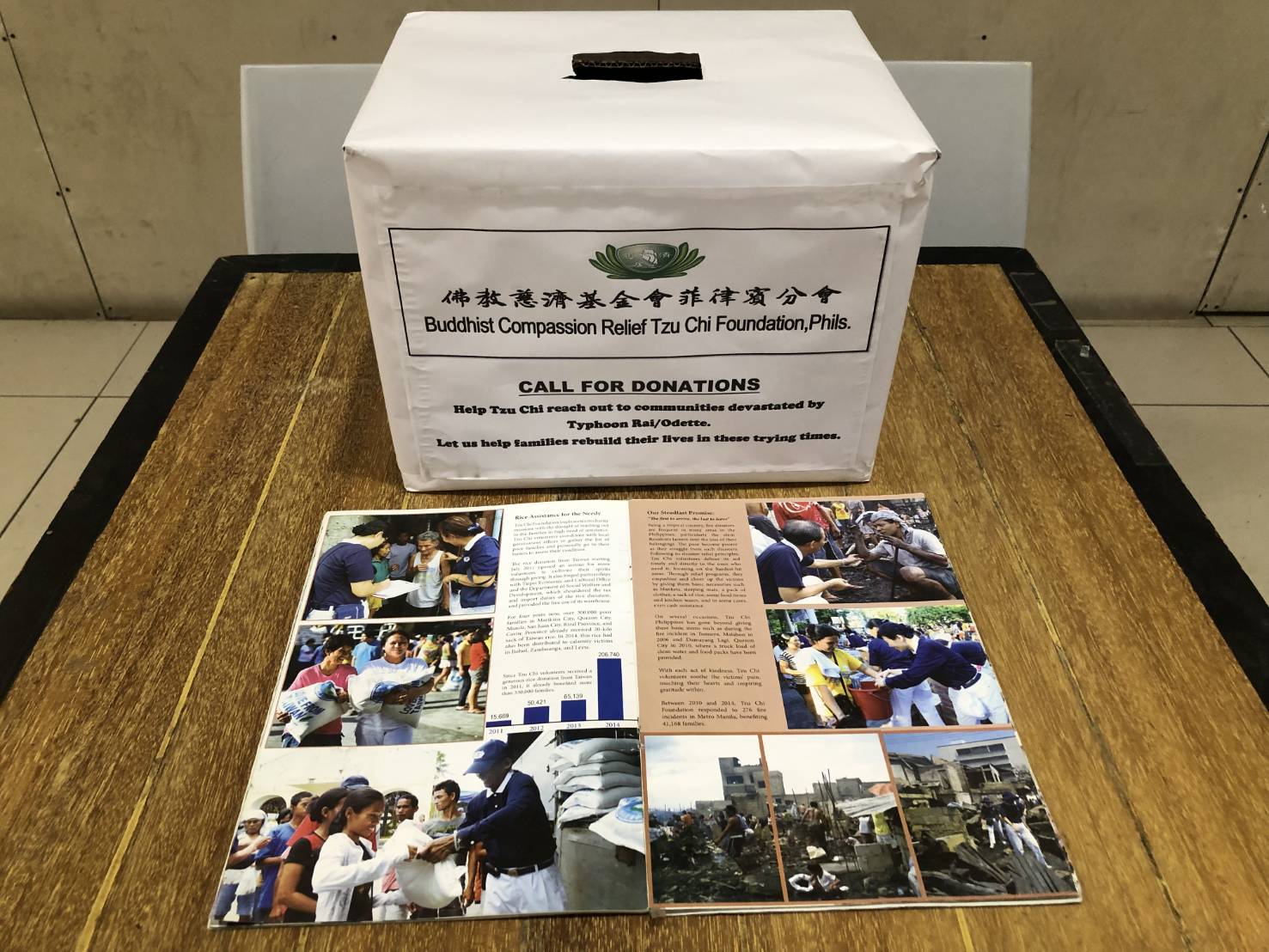 Pledges in any amount are placed inside donation boxes like this. A Tzu Chi pamphlet with pictures of various relief efforts undertaken through the years by the foundation shows donors exactly where their financial help goes.  