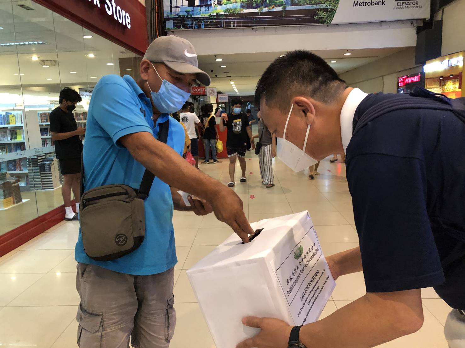 At the Gaisano Mall in Davao City, a volunteer bows in gratitude as a shopper places money in a collection box.