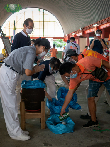 A tricycle driver transfers coins from his coin bank into a collection bag, as volunteers bow in gratitude. 【Photo by Daniel Lazar】