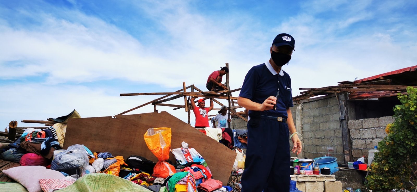 As a Tzu Chi volunteer documents the massive destruction of Typhoon Odette, locals in the background begin rebuilding efforts. 【Photo by Johnny Kwok】