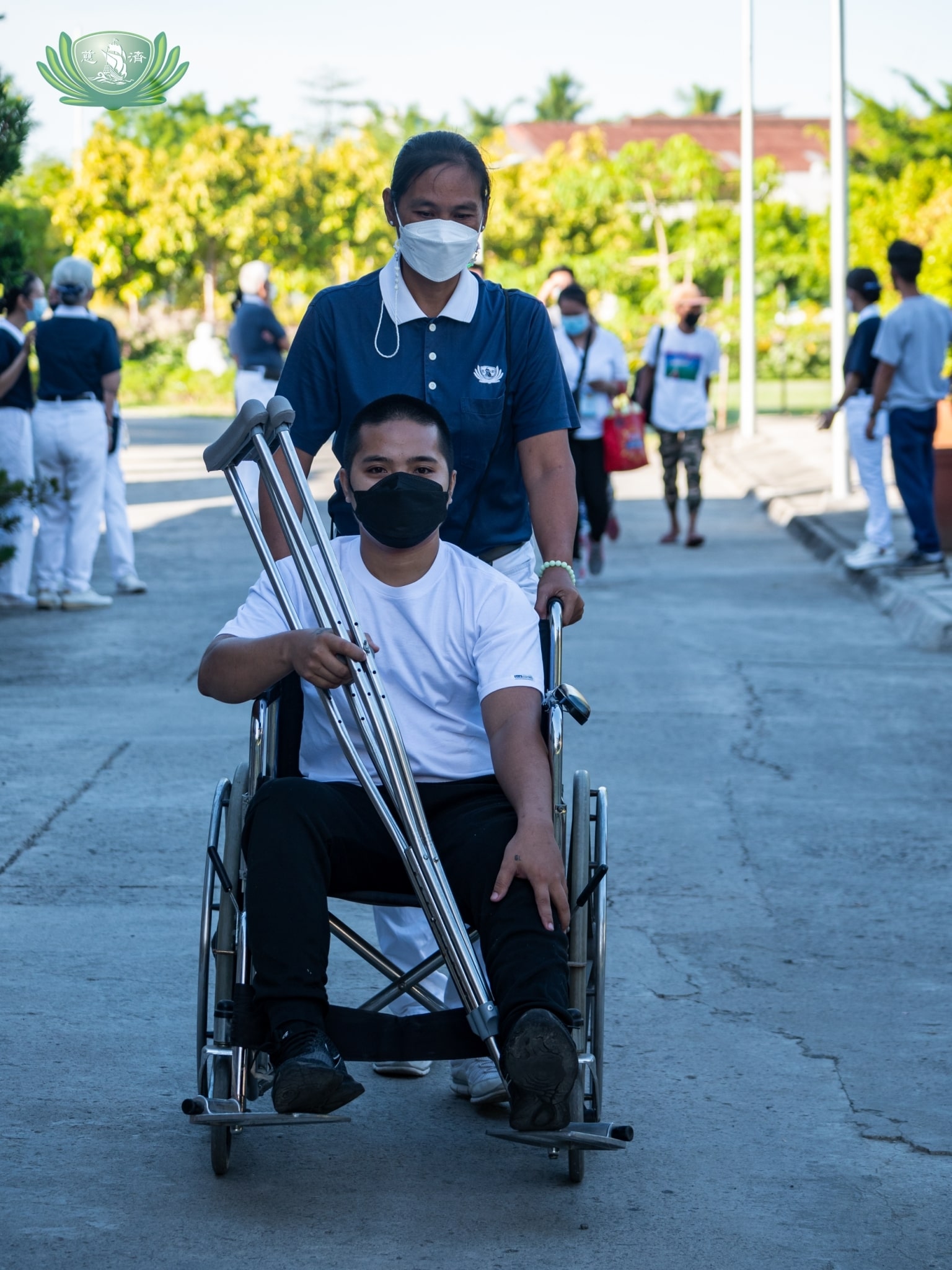 A volunteer pushes beneficiary Christian Dave Delmonte on a wheelchair. Since his operation with metal implant on his left thigh, Delmonte has been able to walk with the aid of crutches.【Photo by Daniel Lazar】
