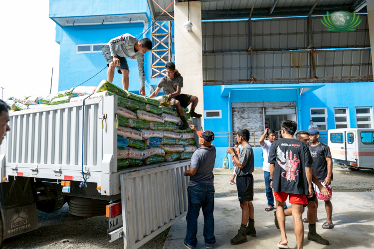 Staff and resident volunteers work together to unload sacks of rice at the PAGCOR Hall ahead of the relief distribution.