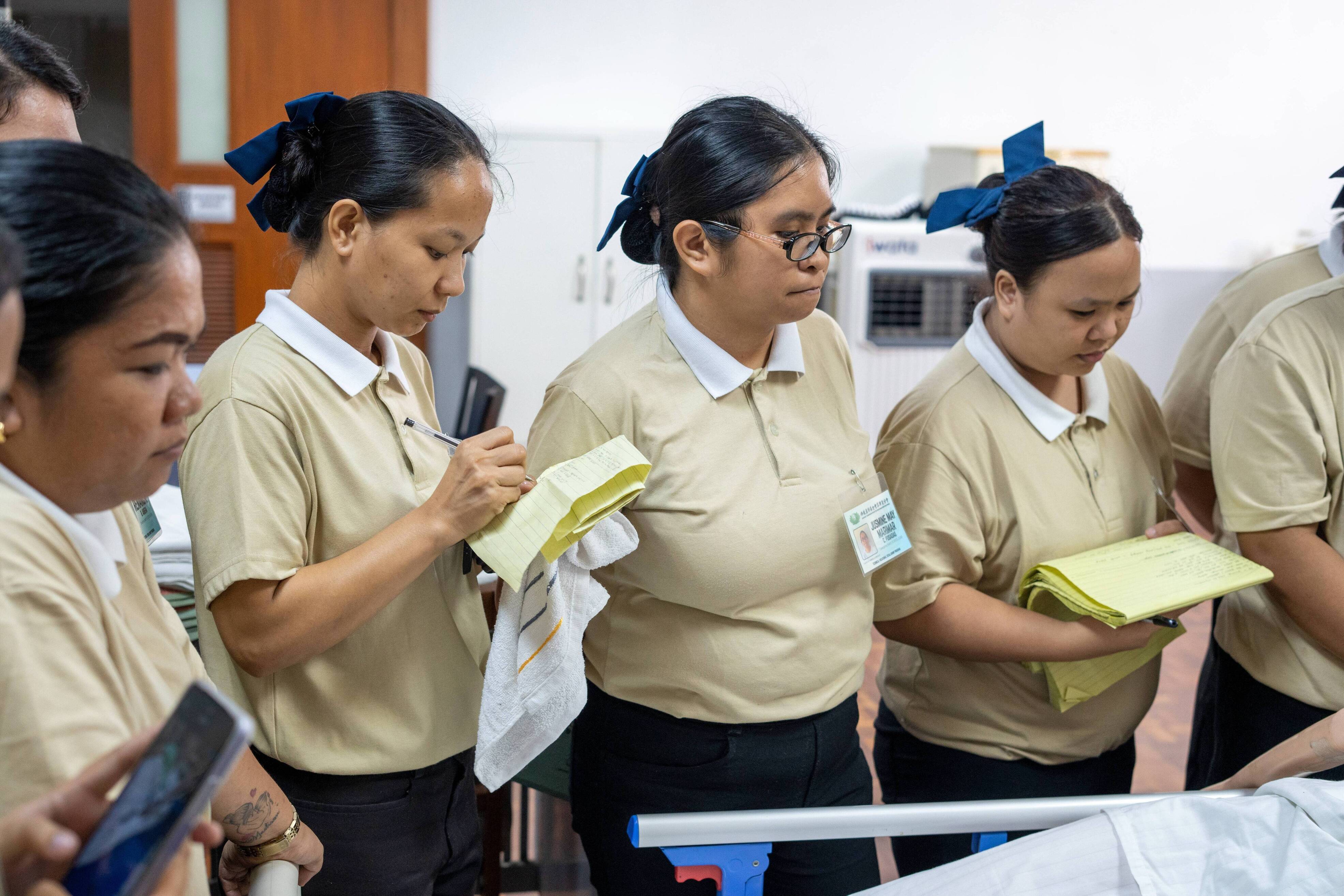 Tech-Voc caregiving scholars of Tzu Chi undergo a clinical assessment demonstration while diligently taking notes. 