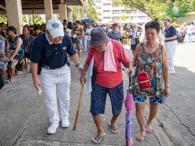 A Tzu Chi volunteer assists a senior citizen in the priority lane during the release of stubs. 