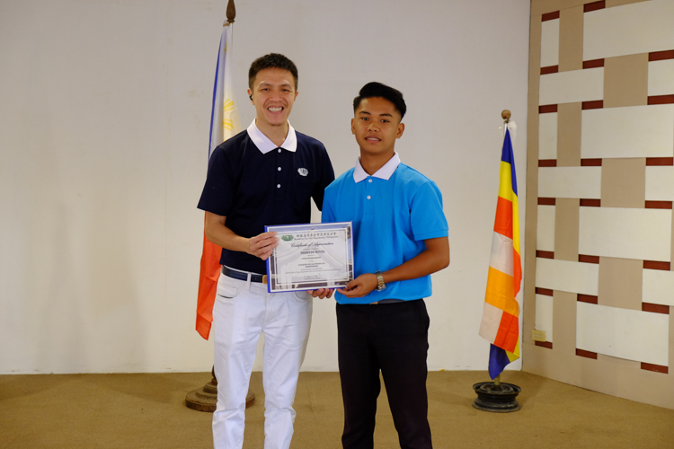 Tzu Chi Zamboanga volunteer Harvey Yap presents a certificate of scholarship to a scholar.