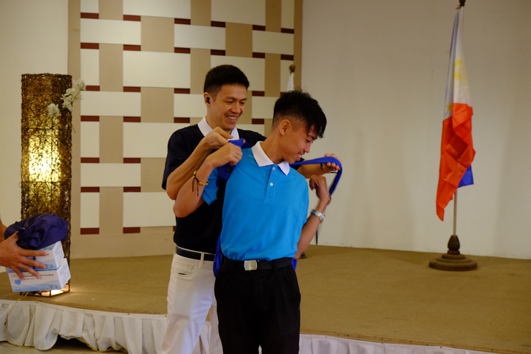 A TechVoc scholar is presented with a bag containing tools during the awarding ceremony.