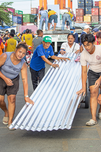 The culture of bayanihan (community spirit) was evident during the distribution of GI sheets. 【Photo by Marella Saldonido】