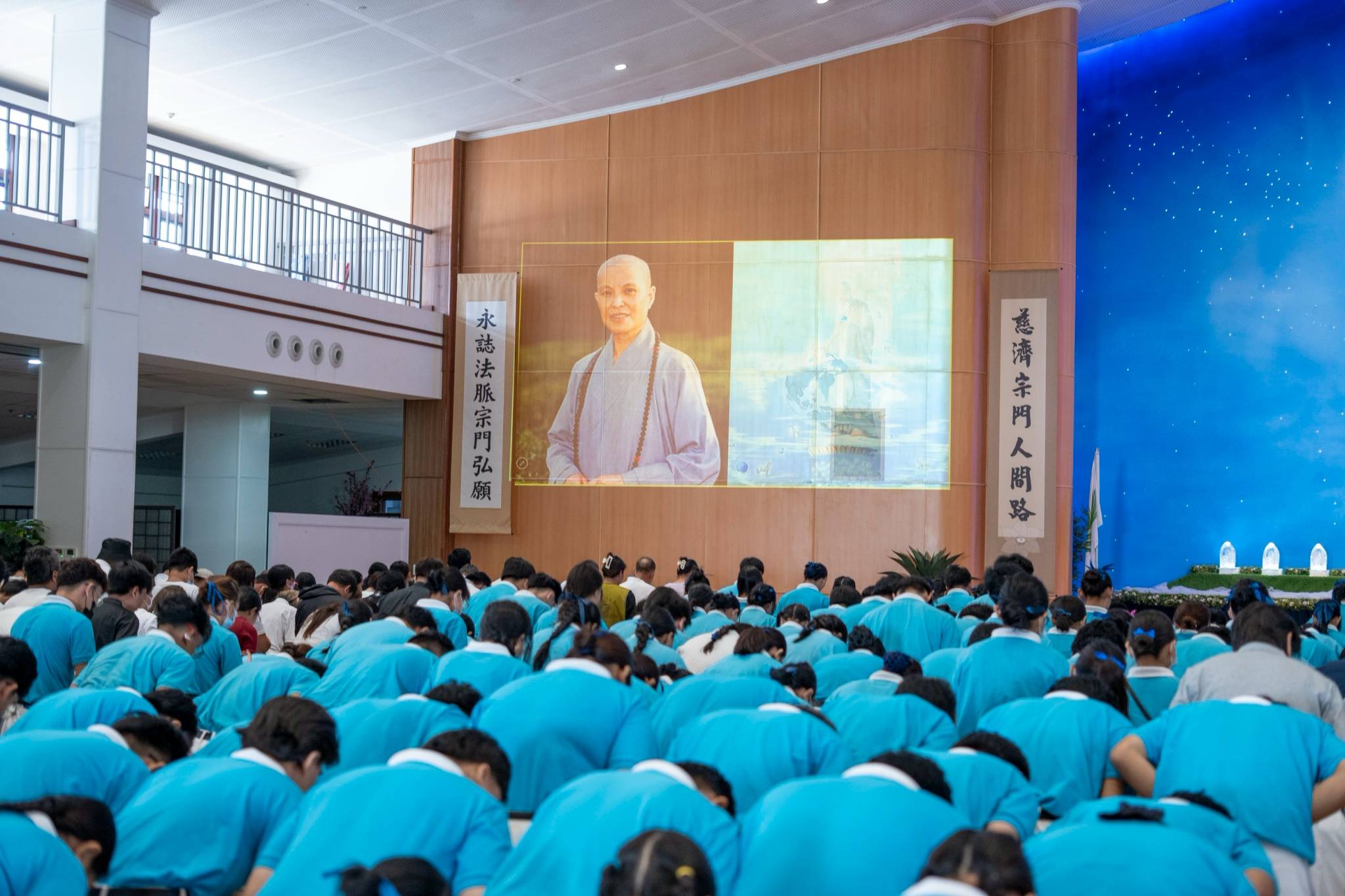 In a moment of reverence, scholars and guests observe quiet decorum during the opening sign of respect to the Buddha.
