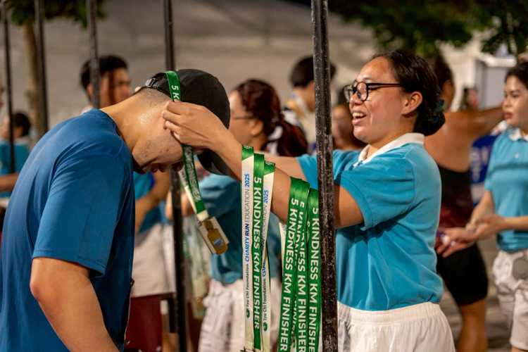 Tzu Chi scholars assist in awarding medals to runners at the finish line.