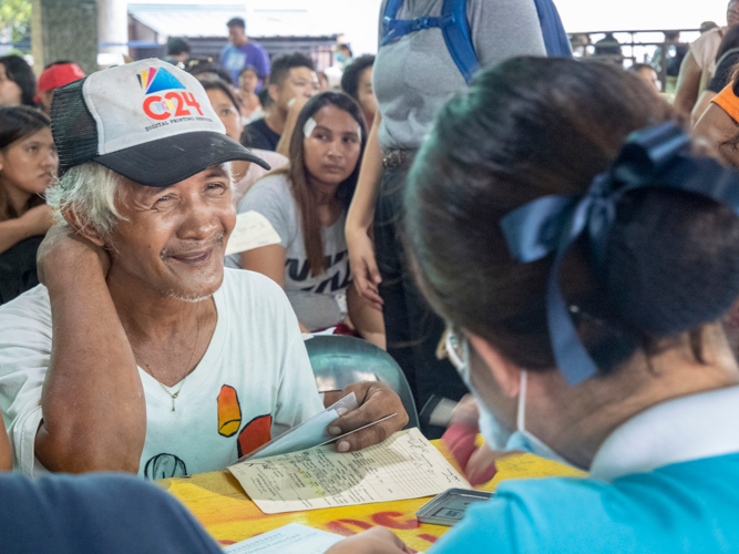 A beneficiary happily receives relief stubs from a Tzu Chi scholar.