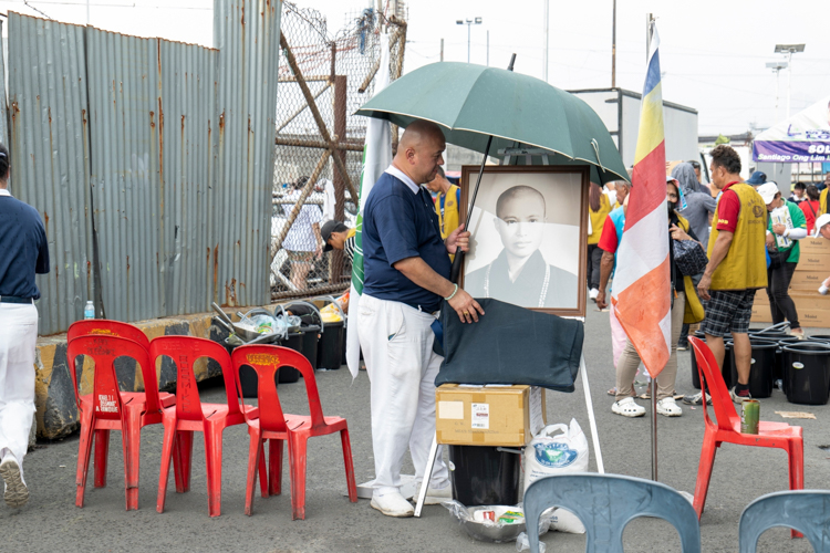 As everyone took cover from an unexpected downpour, this Tzu Chi volunteer stayed to shield a portrait of Tzu Chi founder Dharma Master Cheng Yen with an umbrella.