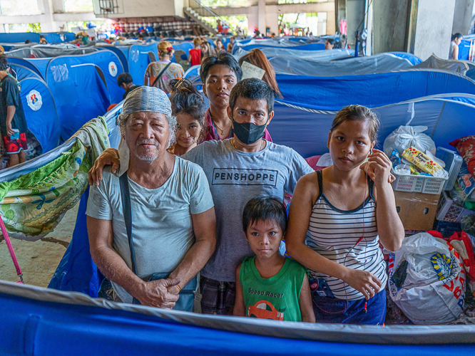 Beneficiary Rosauro Almadin (first from left) and his family currently reside at the Leonardo Fugoso Sport Complex while rebuilding their home in Isla Puting Bato. 【Photo by Harold Alzaga】