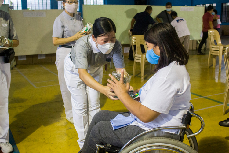 Aside from the sacks of rice, volunteers gave each PWD a Tzu Chi coin bank and vegetarian sticker. 【Photo by Matt Serrano】