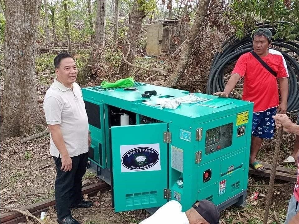 Buenavista Mayor Dave Duallo (left) stands next to the 15kVA generator set provided by the Tzu Chi Foundation. 