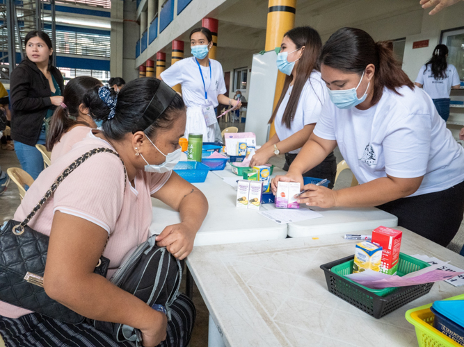 Lovely Dawn Tahil (seated, left) receives medicines for her two children who have a cough and colds. 【Photo by Matt Serrano】