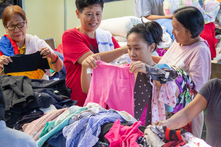 Jessie Mae Gelotin (third from left) looks through different clothing for her children. 【Photo by Marella Saldonido】