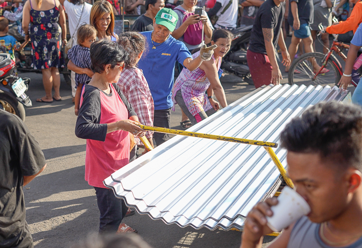 “My husband and I worked together to gather some money to purchase the materials needed to rebuild our house. GI sheets are the only thing missing,” says beneficiary Corazon Baleña  (in red and black). 【Photo by Harold Alzaga】