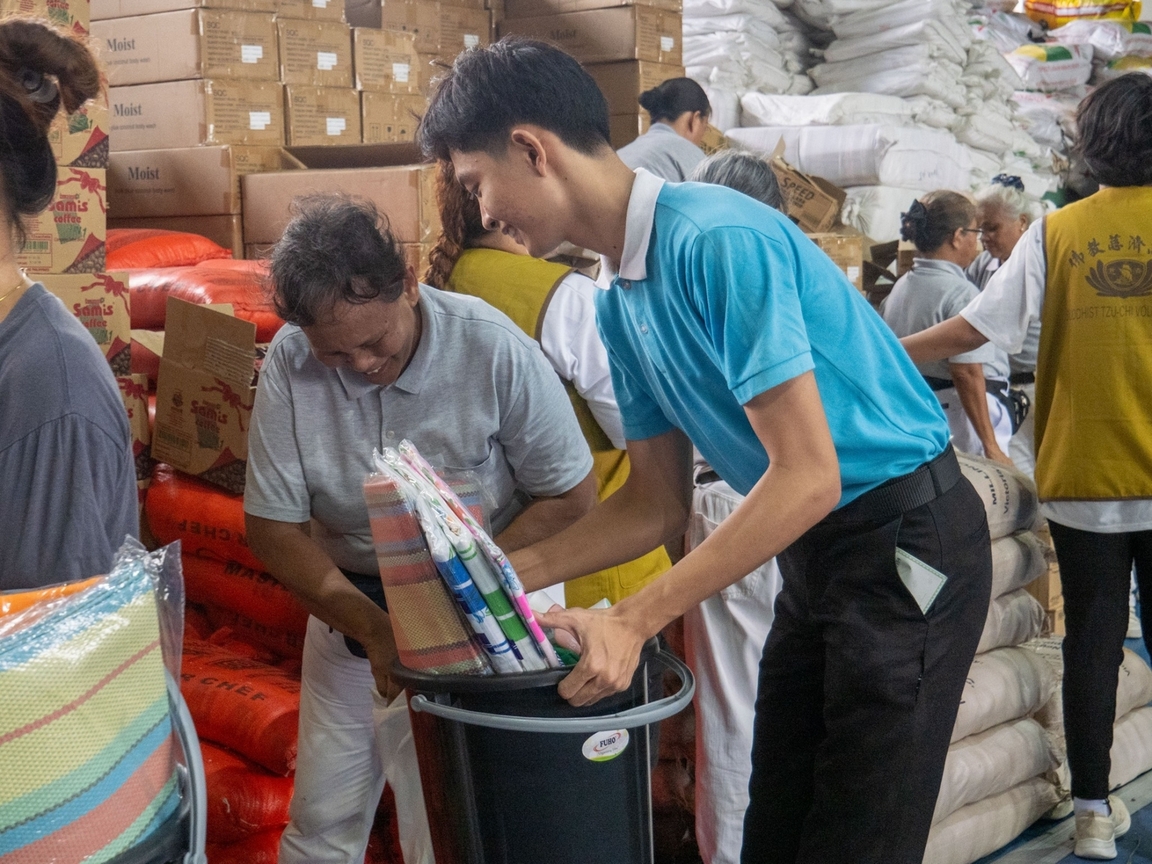 Tzu Chi scholar and San Mateo resident Axcel Rivera ( in blue) is grateful to receive relief goods for his family after experiencing the effects of heavy rains and flooding during Typhoon Carina (Gaemi).
