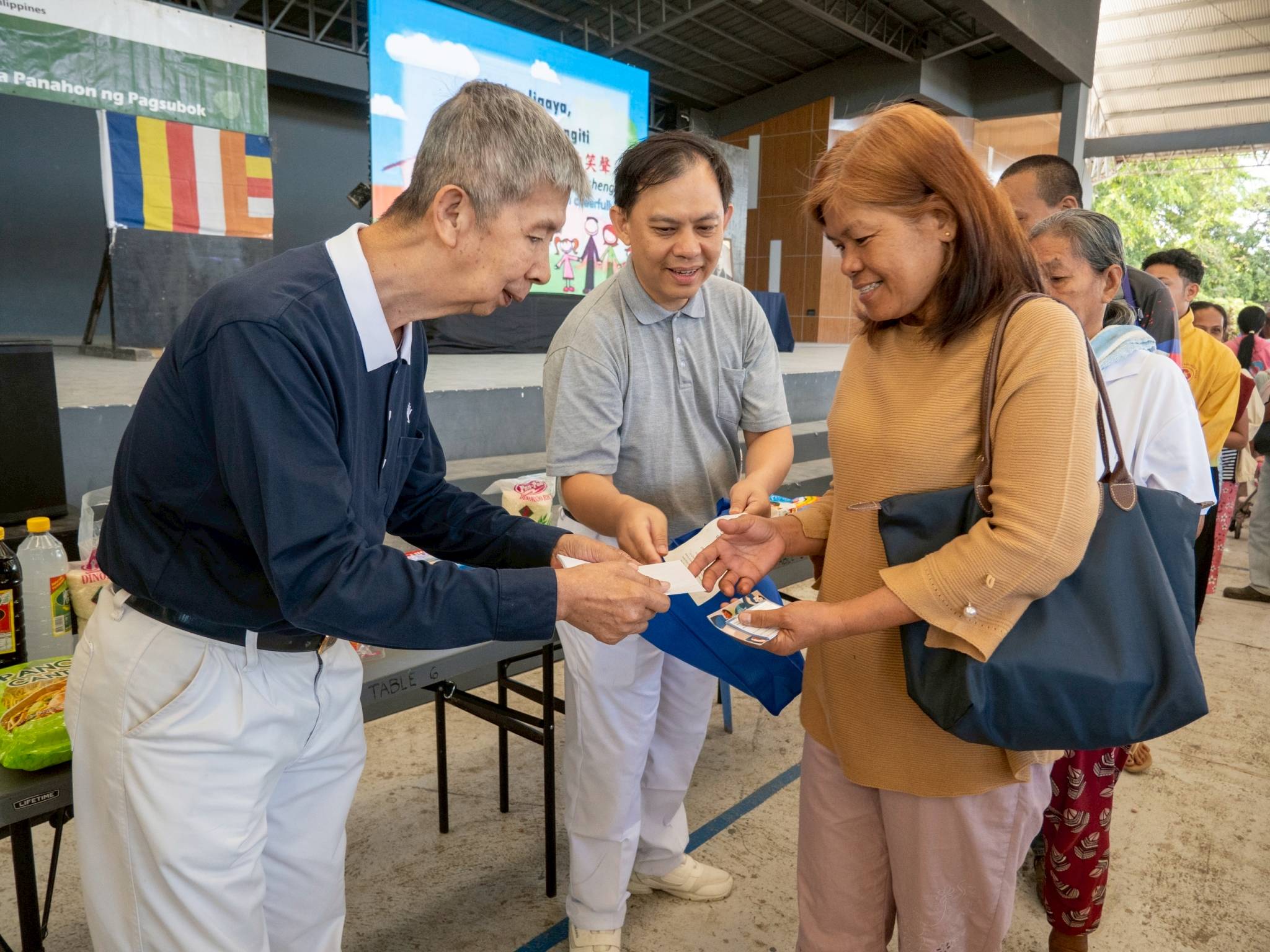 Tzu Chi volunteers distribute grocery gift checks to beneficiaries.