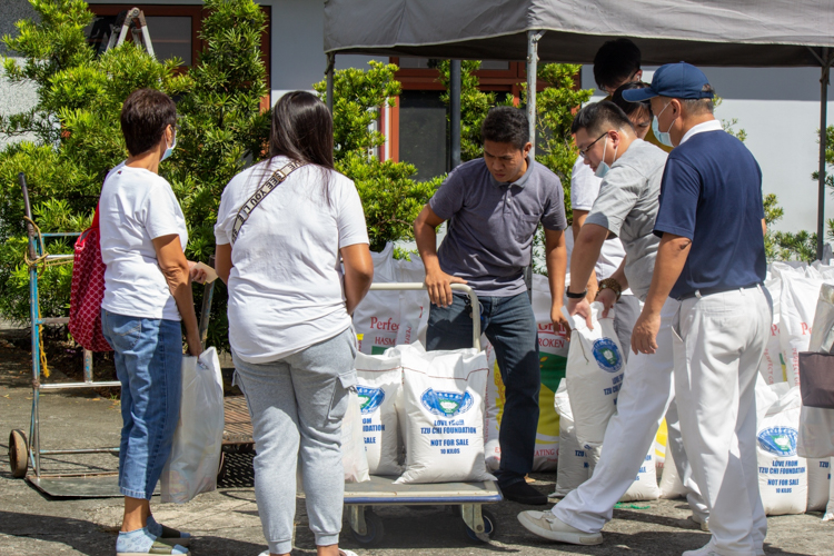 Scholars and medical assistance beneficiaries claim their 10kg sack of rice and grocery items. 【Photo by Marella Saldonido】