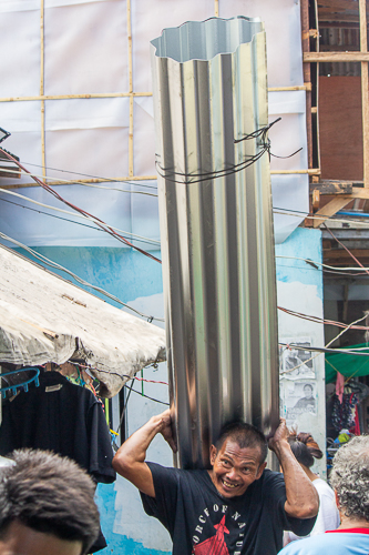 A resident of Isla Puting Bato carries the GI sheets he received from Tzu Chi volunteers. 【Photo by Marella Saldonido】