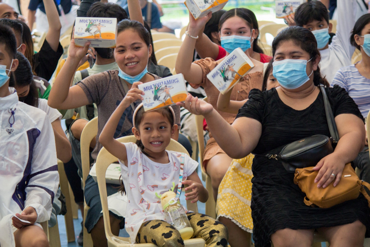 Beneficiaries wave their free supply of multivitamins.【Photo by Matt Serrano】