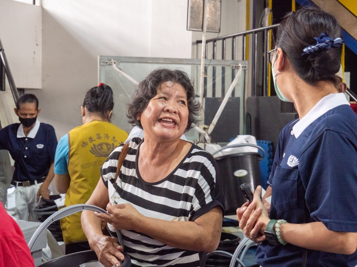 Beneficiary Helen Auxtero (left) thanks a Tzu Chi volunteer for her relief package. 