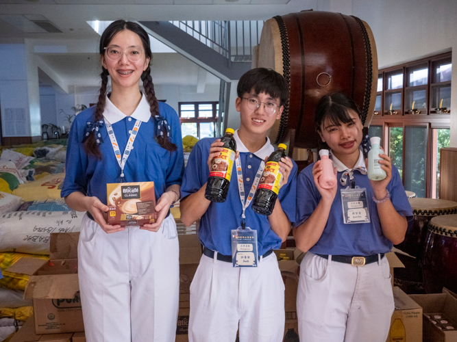 Taiwan’s Tzu Chi Youth (from left) Passion, Duck, and Gorilla display some of the relief items for distribution.