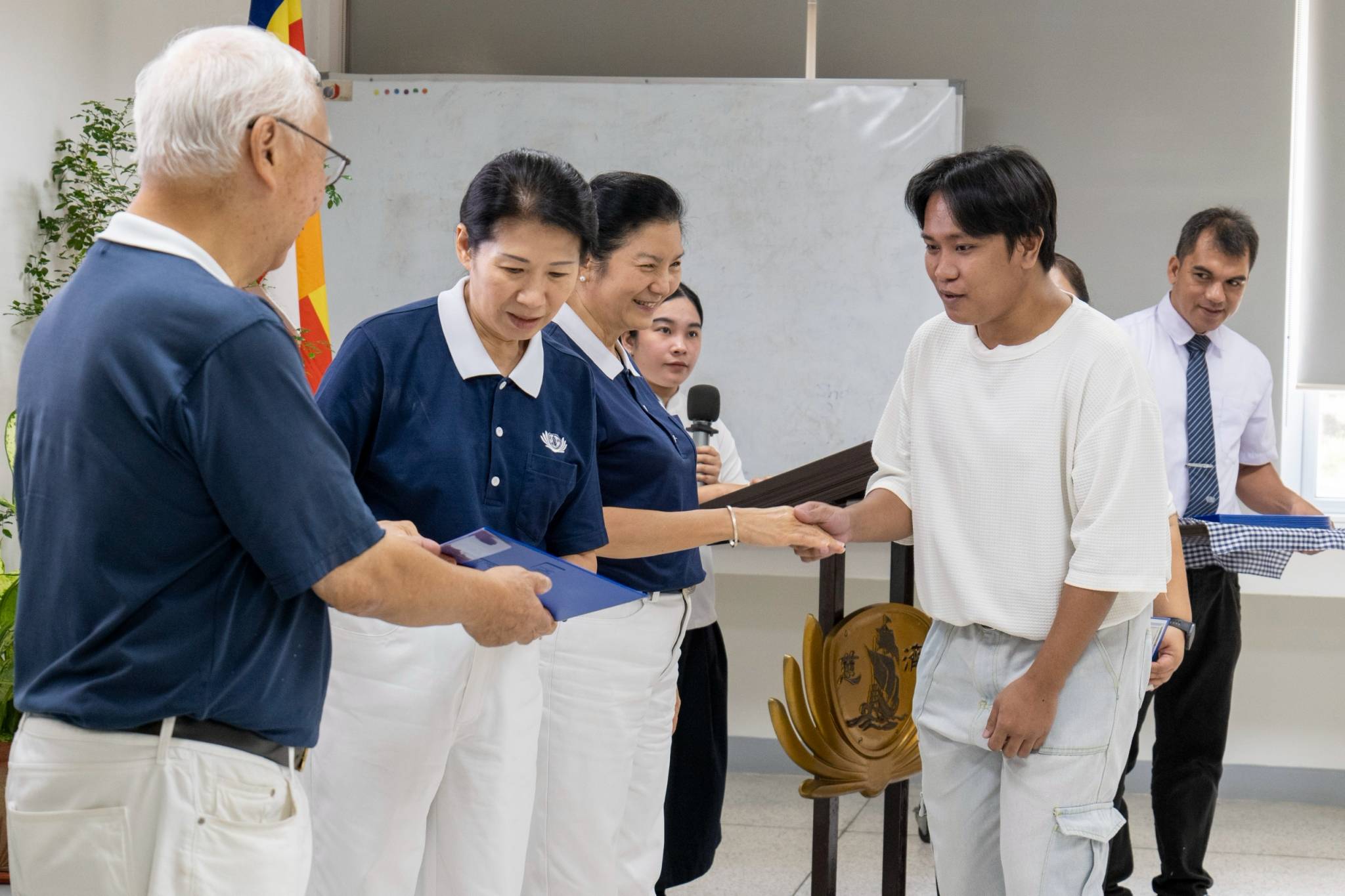 A moment of shared joy: Tech-Voc scholars exchange warm smiles with Tzu Chi volunteers as they proudly accept their scholarship certificates.