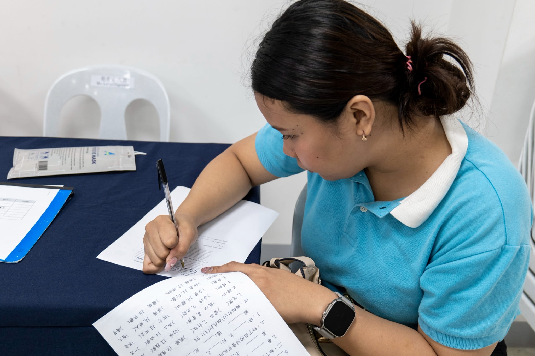 Marry Joy de Leon fills out an exit interview form while waiting for her turn to speak with a Tzu Chi volunteer. 