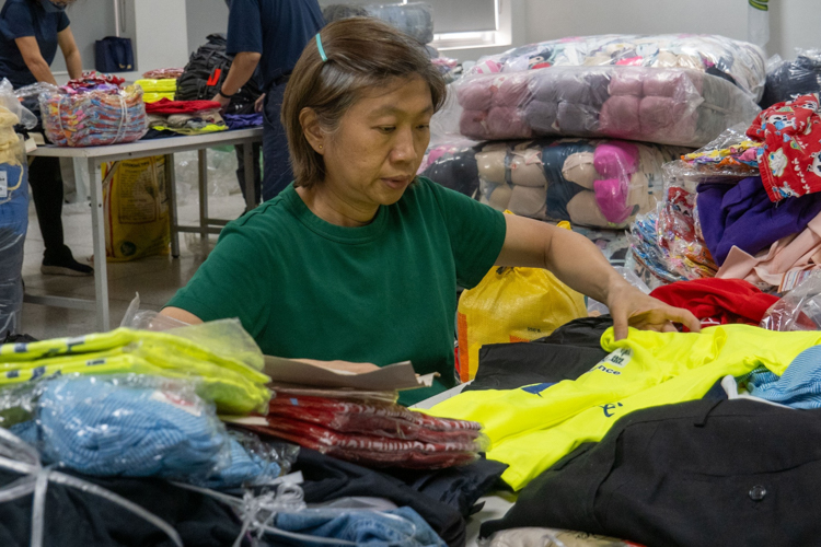 A volunteer helps in folding the sorted clothes.