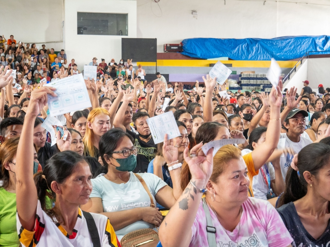 Beneficiaries raise their stamped stubs to be presented to volunteers in claiming their relief goods.