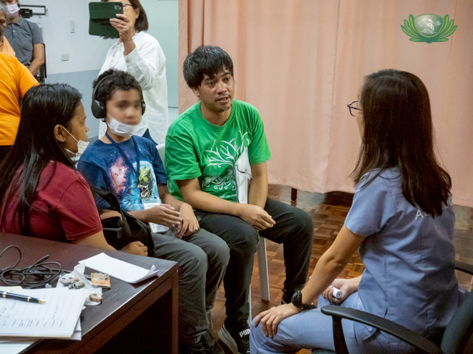 In addition to being diagnosed with Level 2 autism, Jenard Tabuac (in face mask) has mild hearing impairment. Clinic audiologist Kristine Layson (right) meets his parents, Jenny and Gerald Tabuac, to explain how their son can benefit from a hearing aid. 