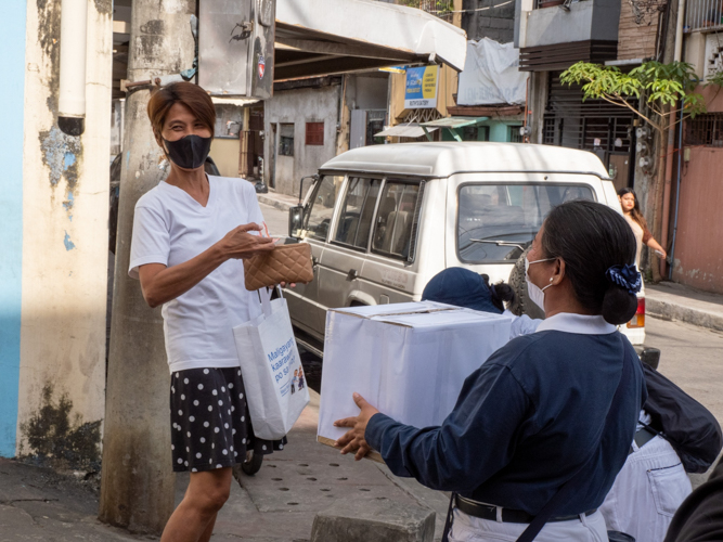 A passerby happily donates money to Tzu Chi’s donation box for the earthquake victims in Turkey and Syria. 【Photo by Marella Saldonido】